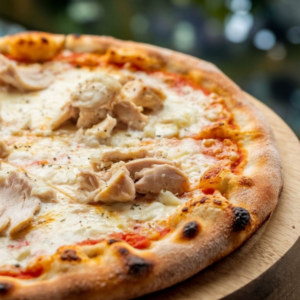 Close-up photograph of Chicken Alfredo Pizza showing texture and toppings